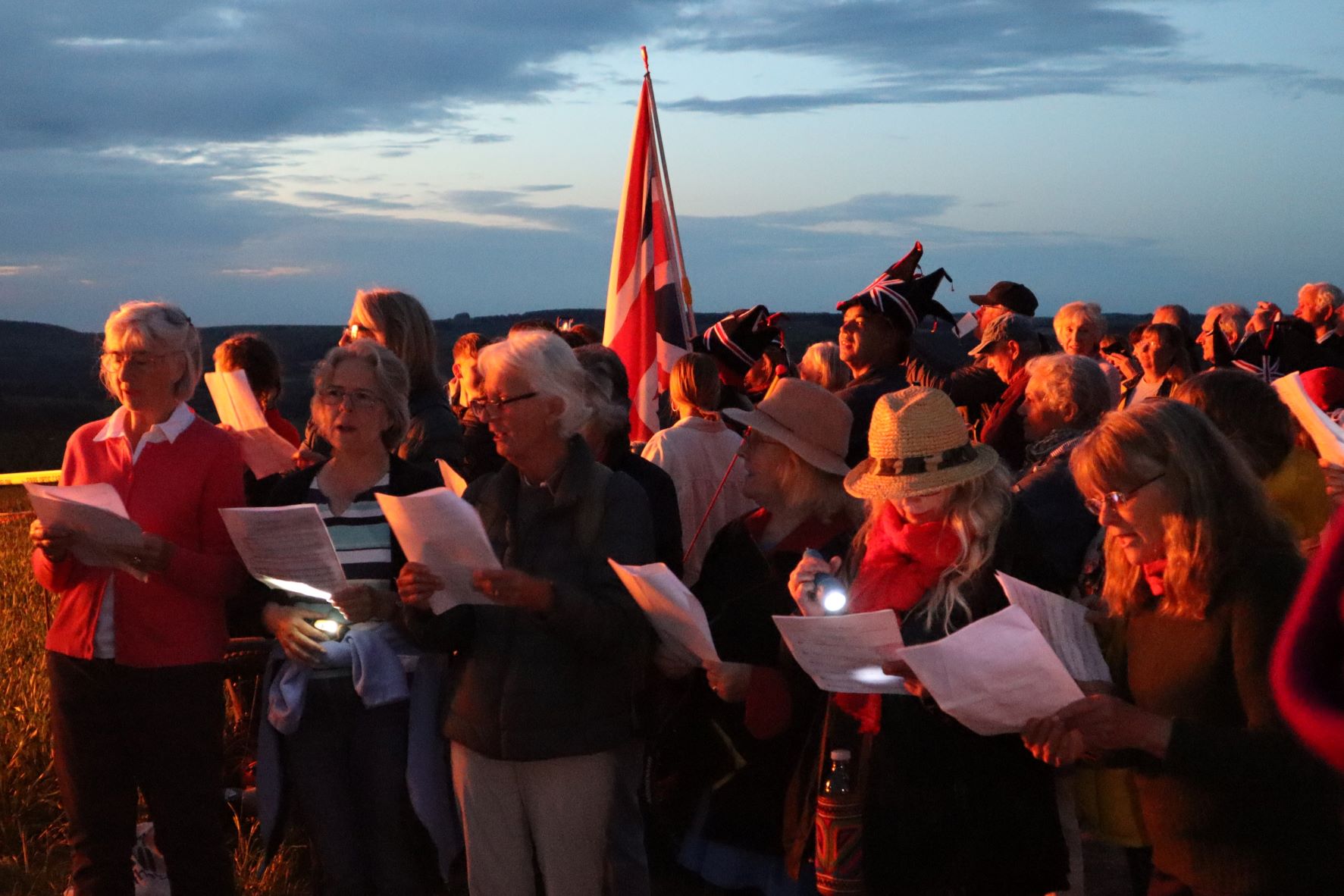 choir sings outside lit by red sunset slow