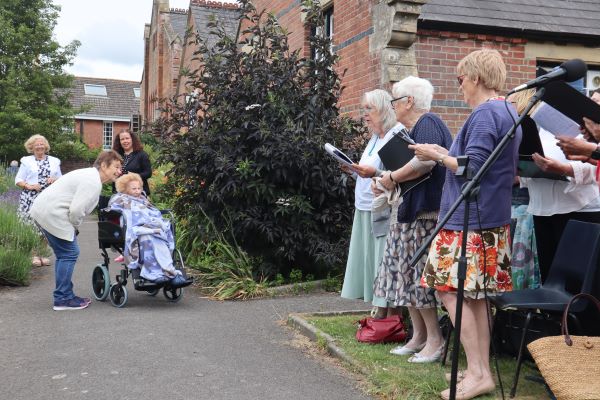 Choir sings outside to elderly woman