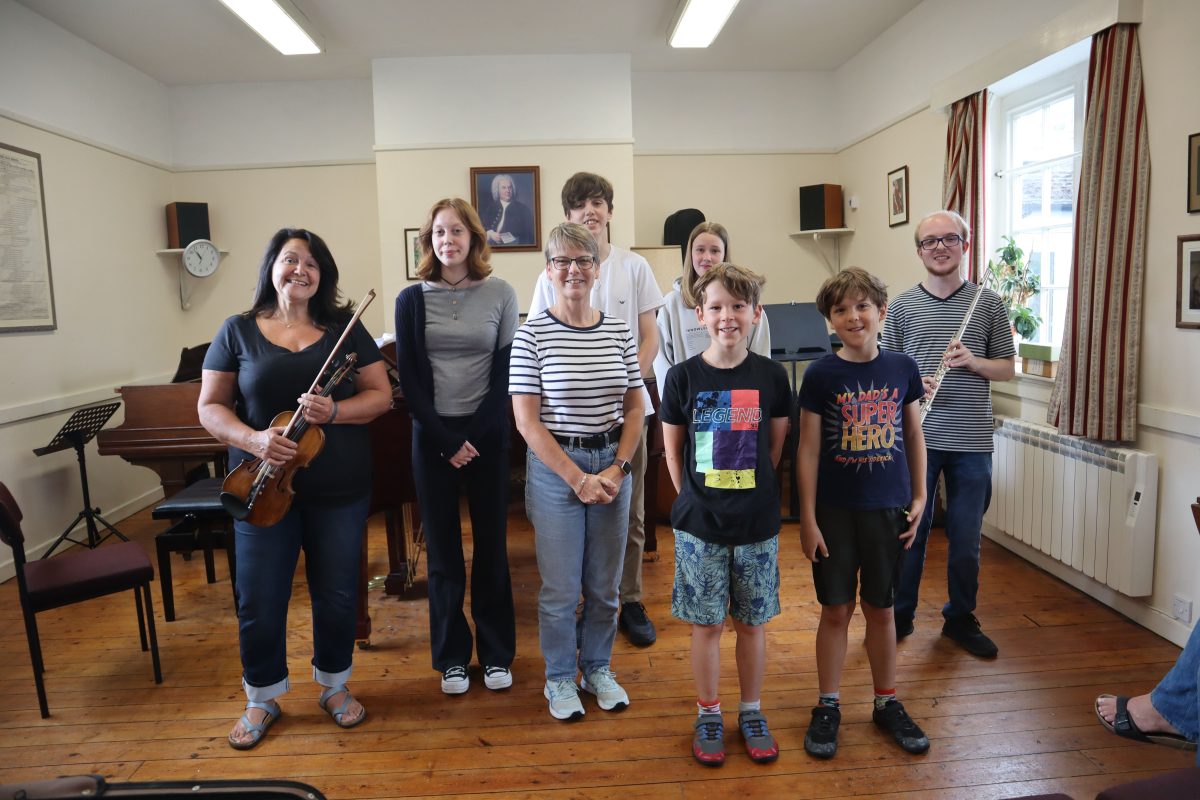 Group of adults and children holding instruments smiling at camera